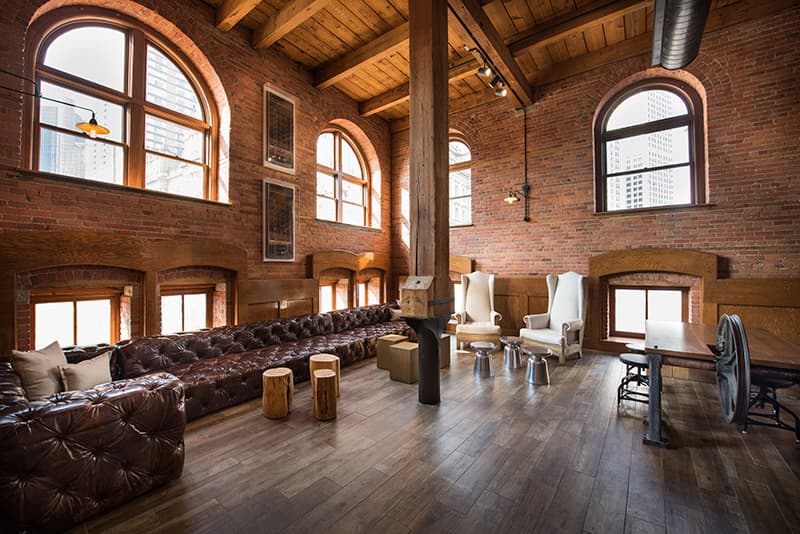 Main lobby to The Globe Building set with two white arm chairs, long tufted leather couch and side tables.